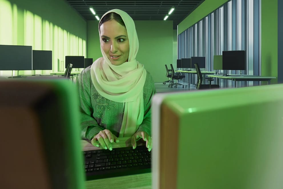 امرأة تعمل على جهاز كمبيوتر في مكتب حديث وتكتب على لوحة المفاتيح باستخدام اتصال 5G من سلام